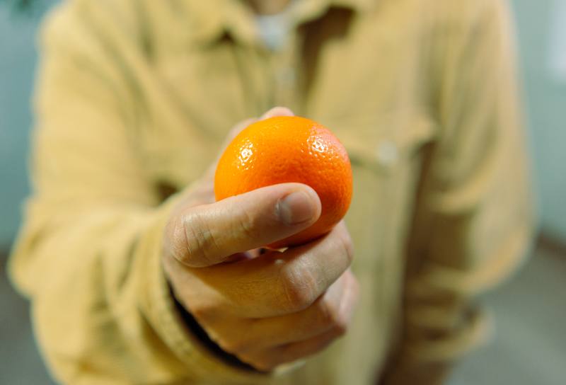 Una mano sostiene una naranja frente a la cámara